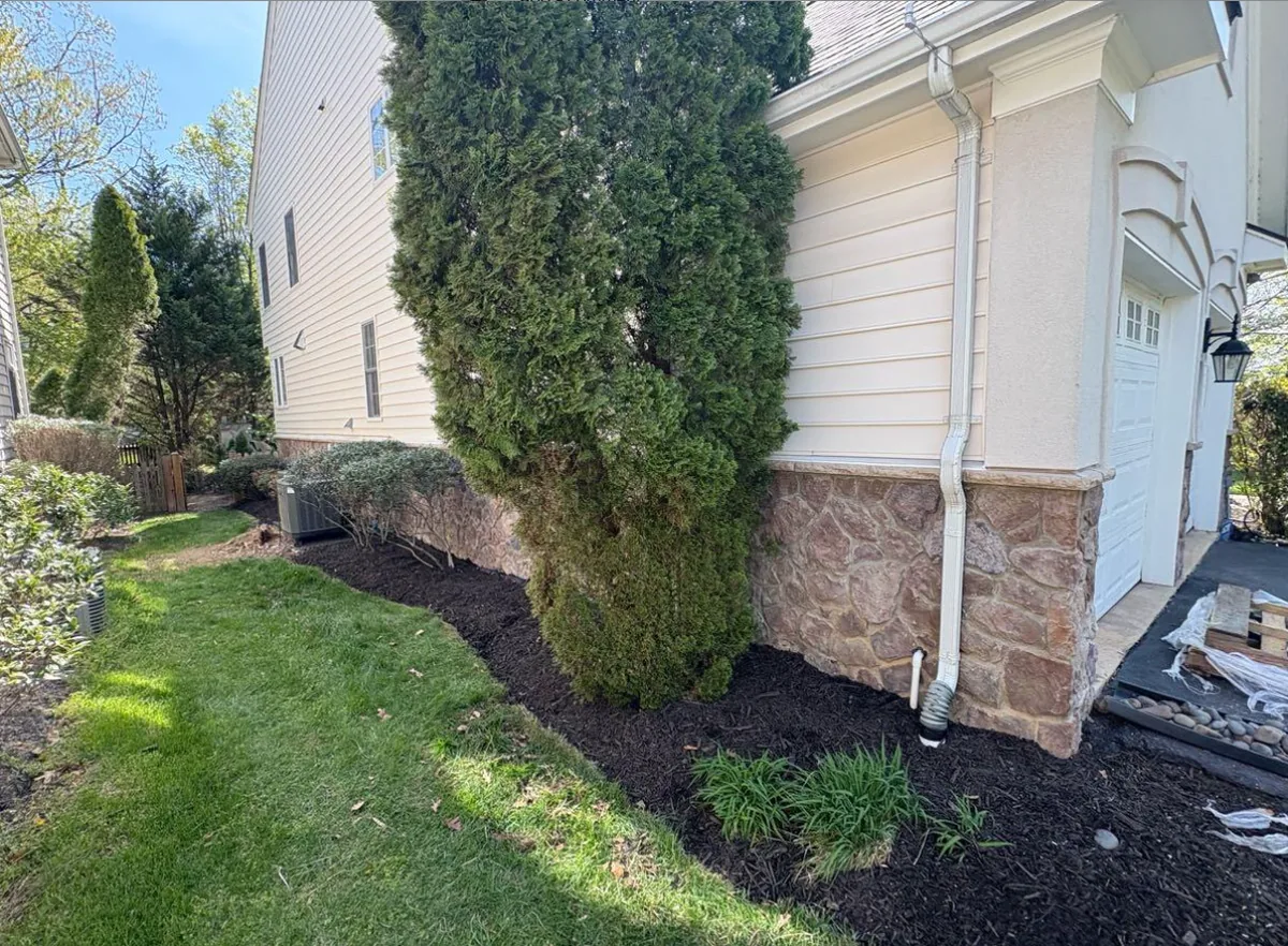 Long foundation bed mulched in dark brown along a stone-and-siding home